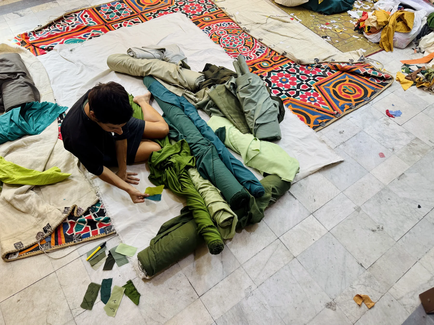 Esmeralda Kosmatopoulos selecting green fabrics on the studio floor in Cairo